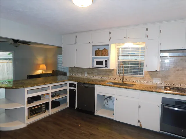 a kitchen with stainless steel appliances white cabinets and wooden floor
