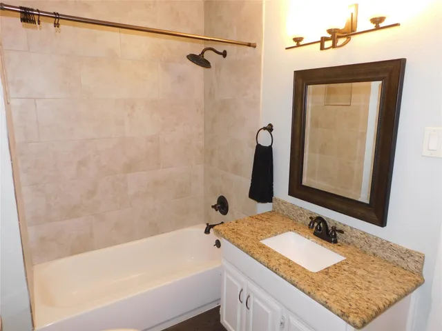 a bathroom with a granite countertop sink mirror vanity and bathtub