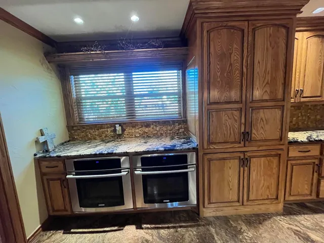 a kitchen with stainless steel appliances kitchen island granite countertop a refrigerator a stove and a sink with wooden floor