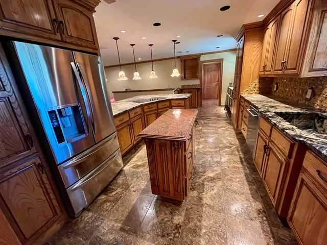 a kitchen with stainless steel appliances granite countertop a refrigerator a stove and a sink