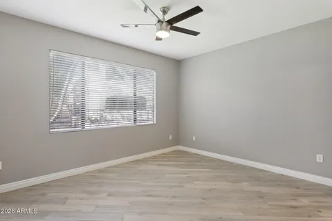 a view of empty room with wooden floor and fan