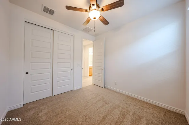 an empty room with closet and a ceiling fan