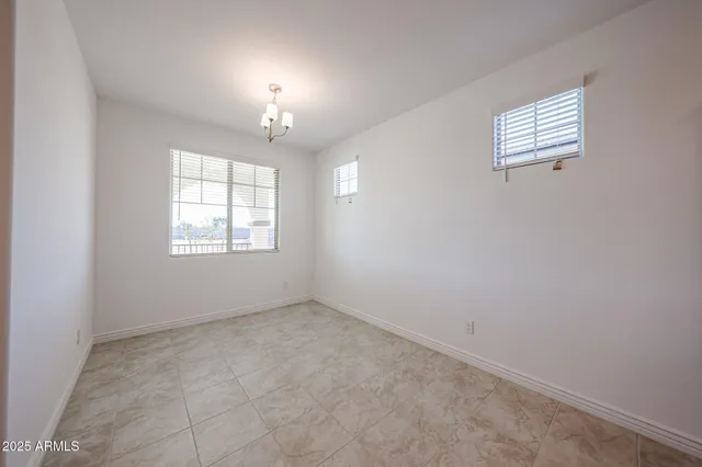 an empty room with windows and chandelier fan