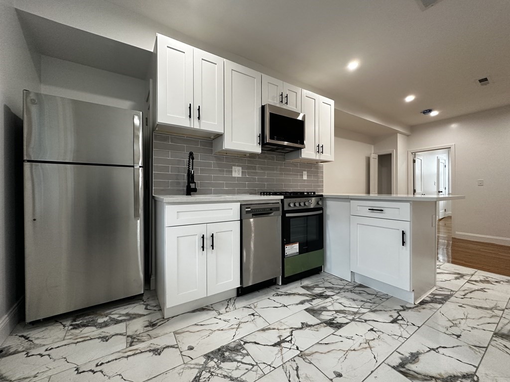 a kitchen with white cabinets stainless steel appliances and a sink