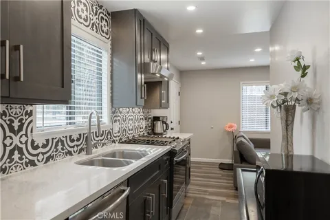 a kitchen with a sink dishwasher a stove and a dining table with wooden floor