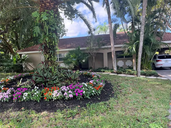 a view of a house with a big yard and flower plants