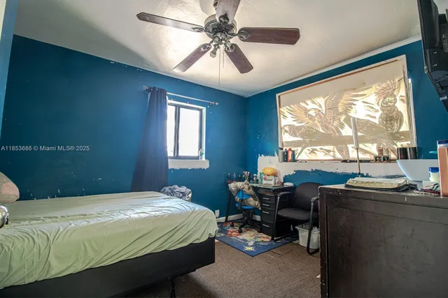 a bedroom with a bed table chair and window