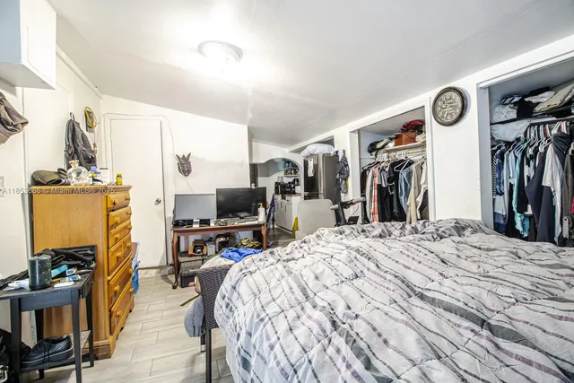 a bed room with a bed mirror and a flat tv screen on a dresser