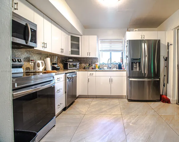 a kitchen with stainless steel appliances granite countertop a stove top oven a refrigerator and a sink