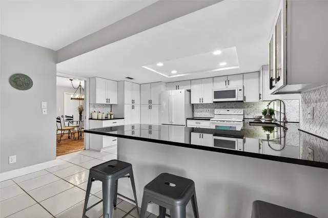 a kitchen with stainless steel appliances granite countertop a sink a stove a refrigerator cabinets and chairs