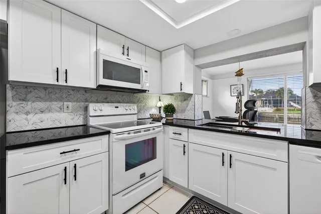 a kitchen with granite countertop white cabinets and white appliances
