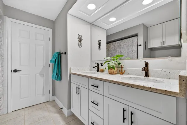 a spacious en suite bathroom with a granite countertop sink and a mirror