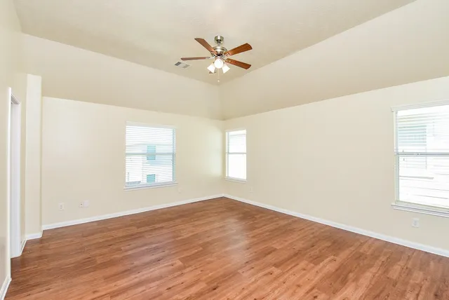 a view of a room with wooden floor and a ceiling fan