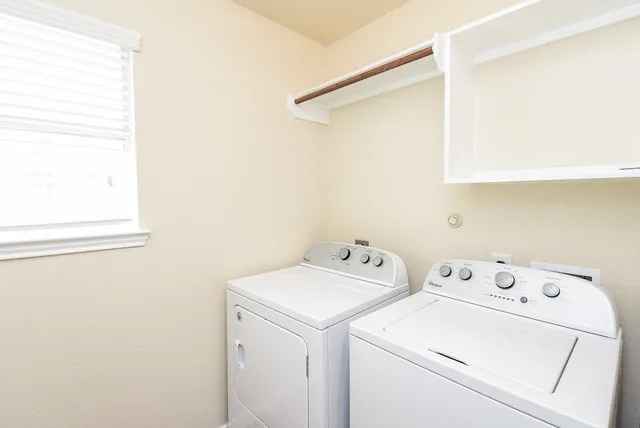 a view of washer and dryer with bathroom in the background