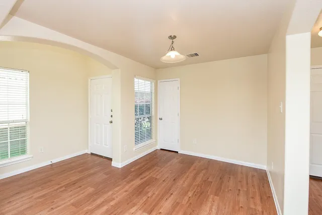 an empty room with wooden floor and windows