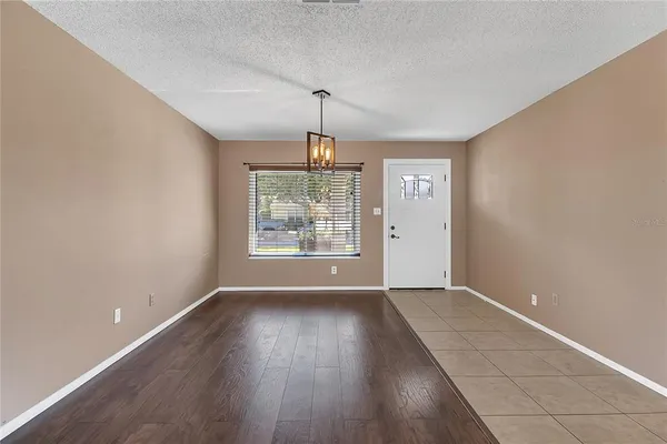an empty room with wooden floor chandelier and windows
