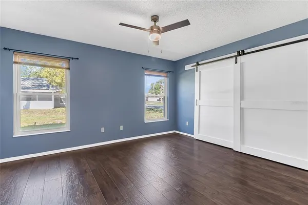 a view of an empty room with a window and wooden floor