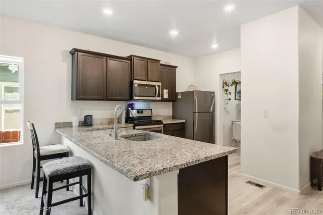 a kitchen with kitchen island granite countertop a table chairs microwave and refrigerator