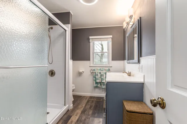 a bathroom with a sink a toilet a mirror and shower