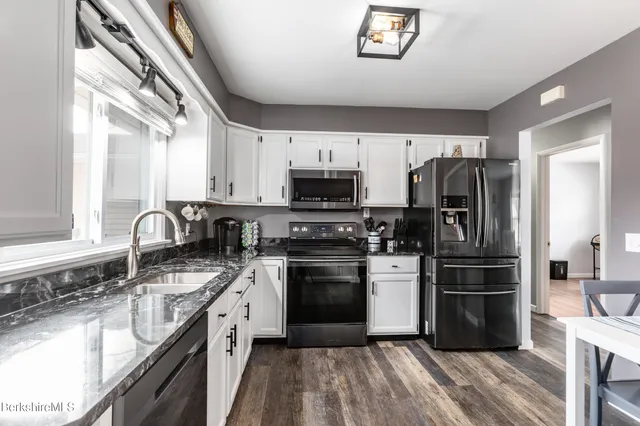a kitchen with granite countertop a refrigerator stove and sink