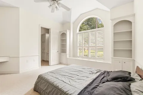 a bedroom with a bed next to a window with a chandelier