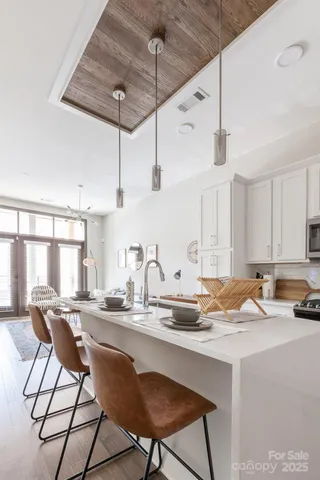 a kitchen with stainless steel appliances granite countertop a sink a stove a refrigerator and chairs