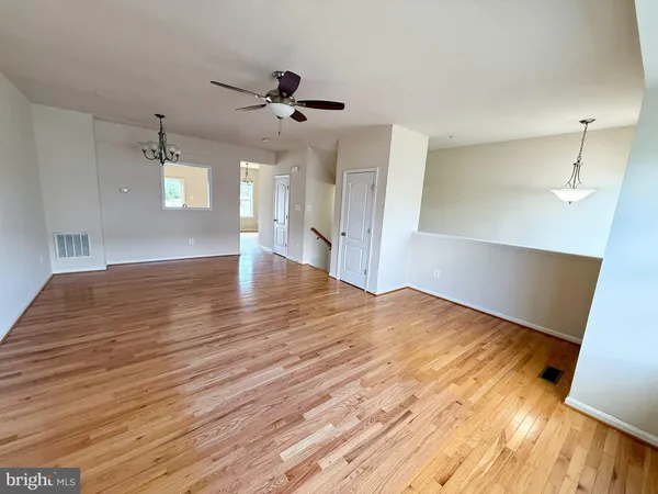 a view of empty room with wooden floor and ceiling fan