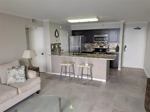 a kitchen with stainless steel appliances kitchen island granite countertop a refrigerator a stove top oven a sink and dishwasher