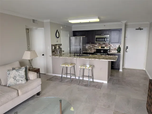 a kitchen with stainless steel appliances kitchen island granite countertop a refrigerator a stove top oven a sink and dishwasher