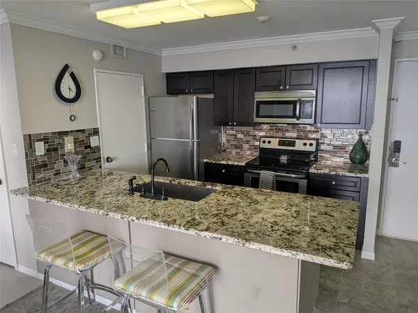a kitchen with kitchen island granite countertop a sink stove and refrigerator