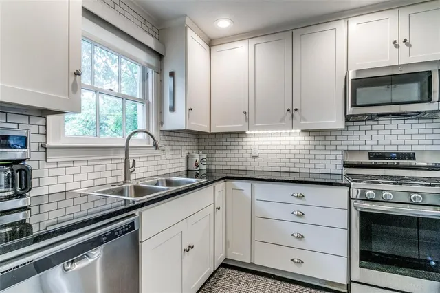 a kitchen with white cabinets stainless steel appliances and a sink