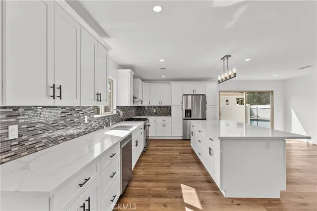 a large kitchen with stainless steel appliances granite countertop a lot of counter space and wooden floors
