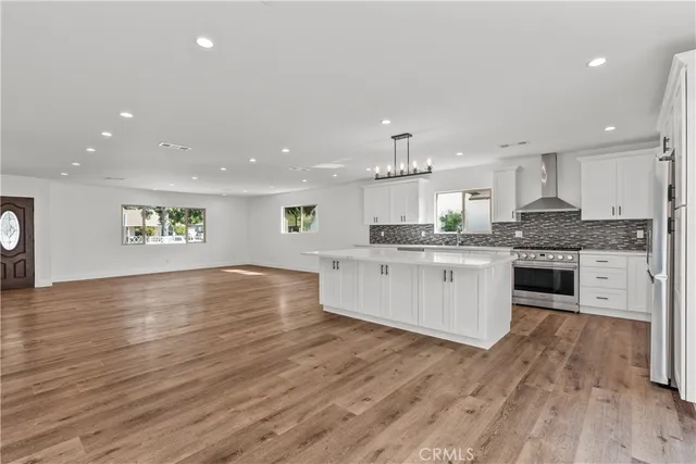 a large kitchen with stainless steel appliances granite countertop a stove a sink dishwasher and a oven with white cabinets