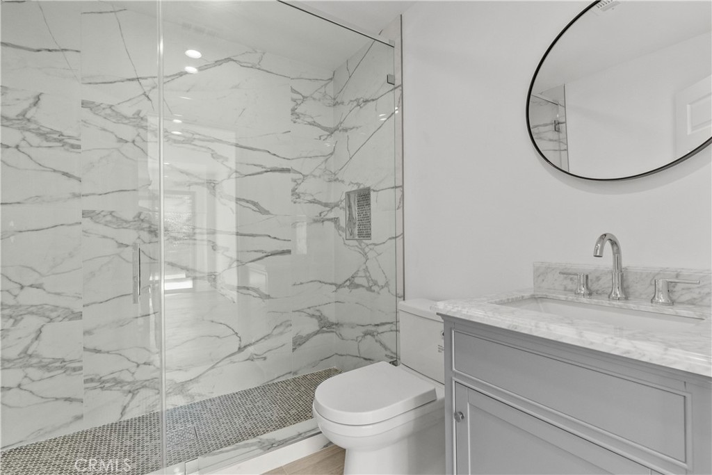 7419 Gloria Avenue Van Nuys, CA 91406 - Photo 47 of 51 a bathroom with a granite countertop sink a toilet and a mirror