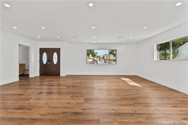 a view of an empty room with window and wooden floor