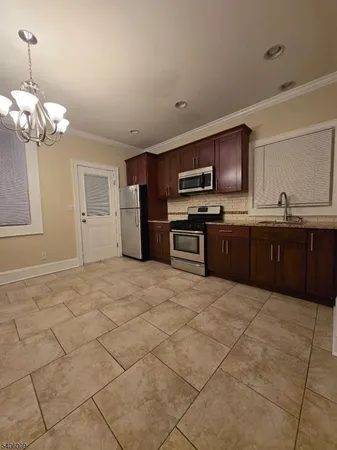 a large kitchen with kitchen island granite countertop a stove top oven a sink a counter space and cabinets