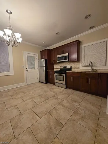 a large kitchen with kitchen island granite countertop a stove top oven a sink a counter space and cabinets