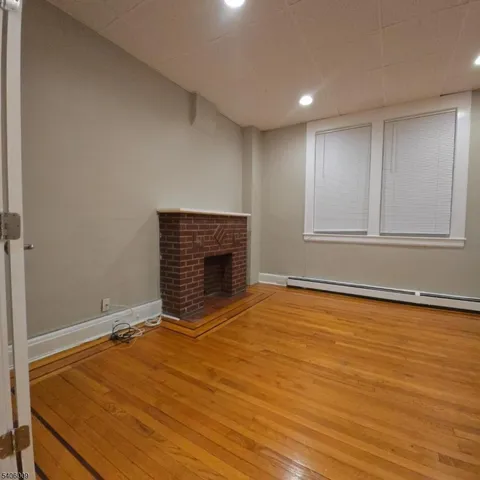 a view of an empty room with a fireplace and wooden floor
