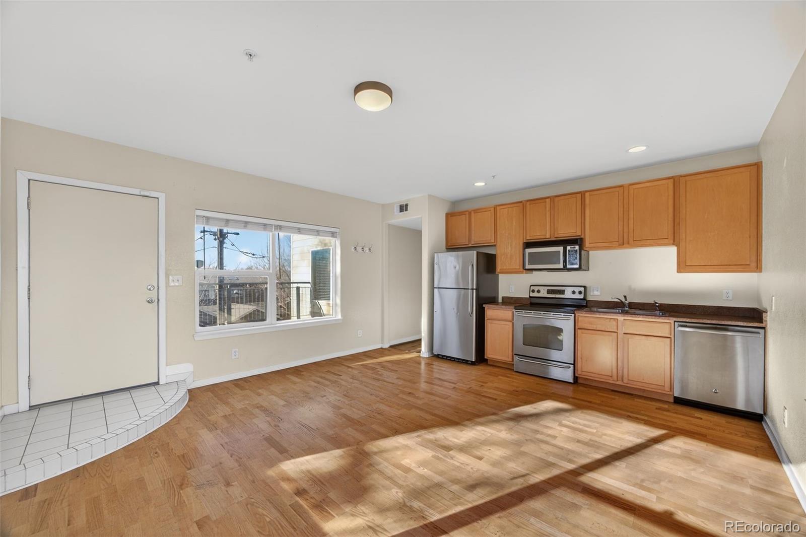 2389 South High Street, Unit 4 Denver, CO 80210 - Photo 6 of 32 a kitchen with stainless steel appliances granite countertop a stove top oven a sink dishwasher and a refrigerator with wooden floor