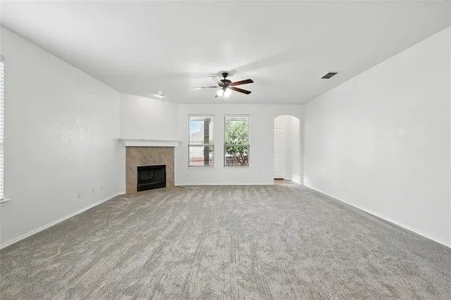 an empty room with windows and fireplace