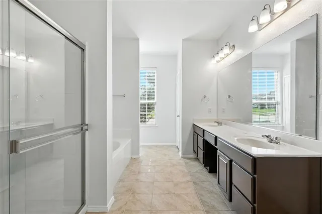 a spacious bathroom with a tub sink shower and mirror