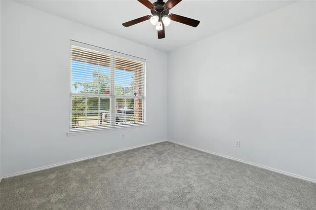 an empty room with a window and a fan