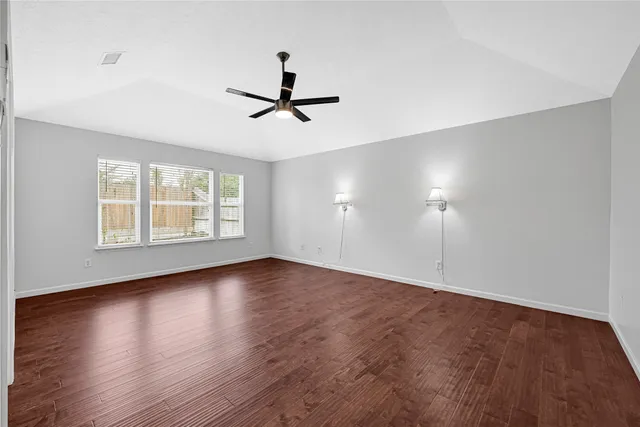 a view of empty room with wooden floor and fan