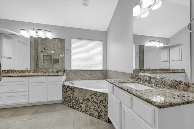 a bathroom with a granite countertop double vanity sink and a mirror
