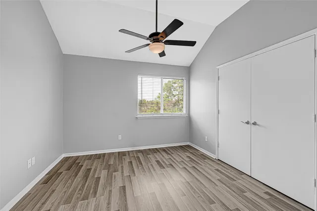 a view of empty room with wooden floor and fan