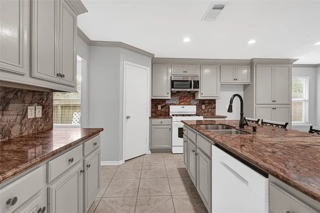 a kitchen with kitchen island granite countertop a sink stove and cabinets
