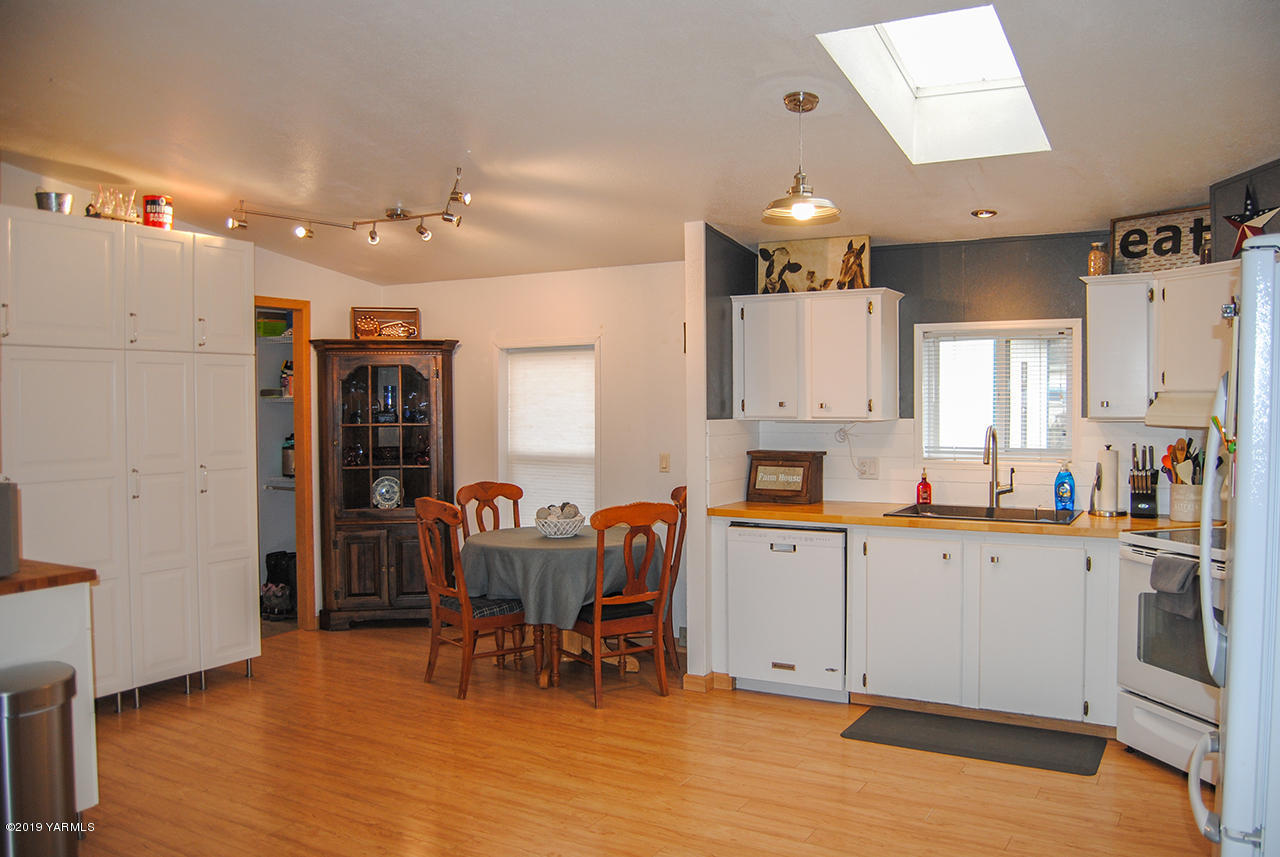 4971 Beam Road Granger, WA 98932 - Photo 5 of 24 a kitchen with stainless steel appliances granite countertop a refrigerator a sink dishwasher a dining table and chairs with wooden floor