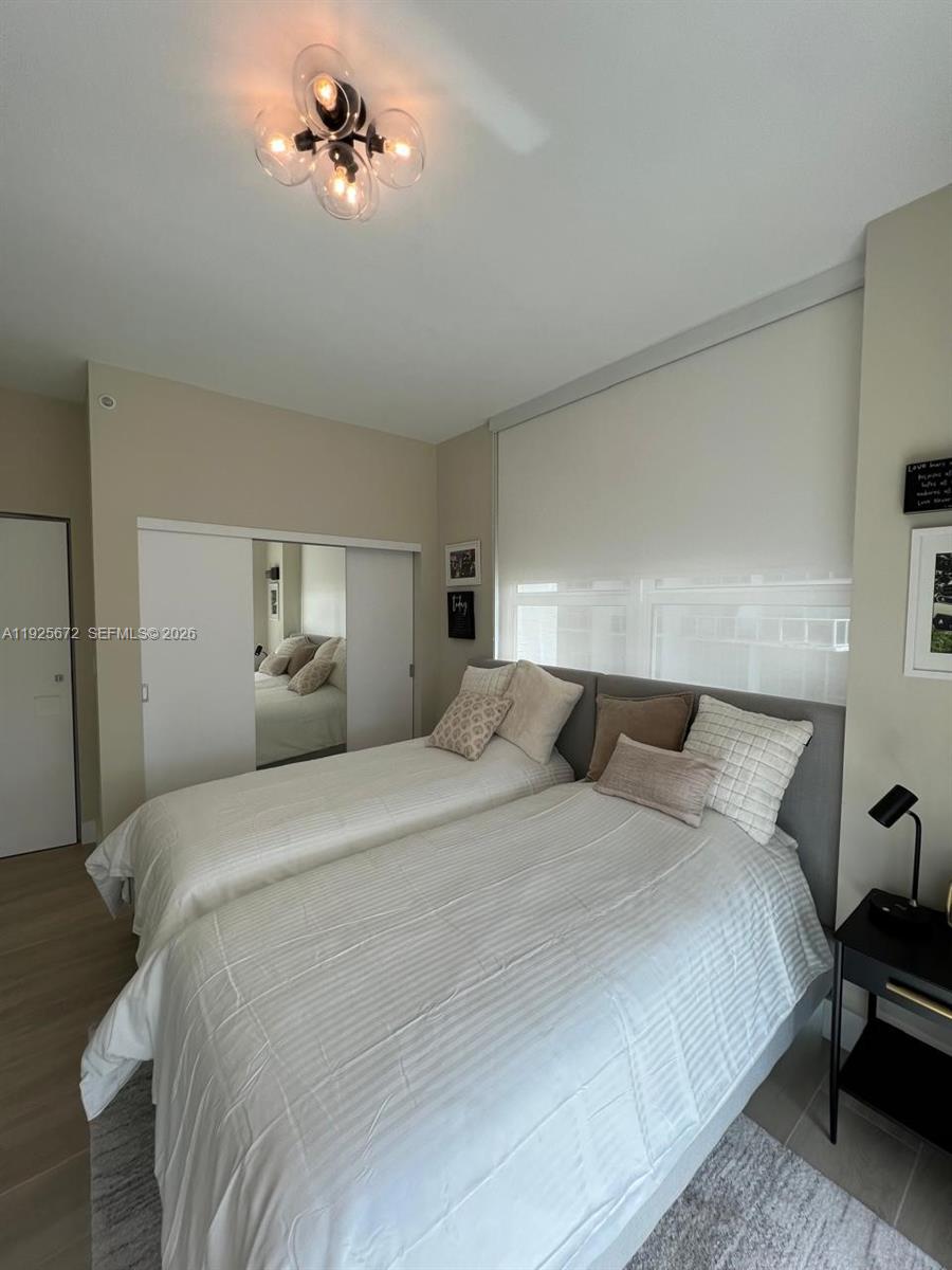 31 Southeast 5th Street, Unit 3921 Miami, FL 33131 - Photo 19 of 34 a bedroom with bed a chandelier and a couch