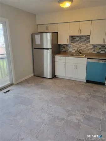 a kitchen with stainless steel appliances granite countertop a refrigerator a stove a sink and a granite counter tops with white cabinets