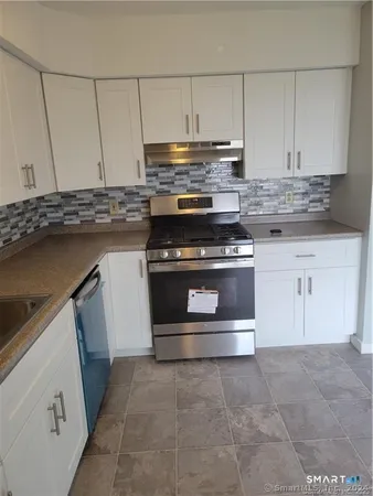 a kitchen with granite countertop a stove top oven and cabinets
